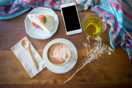 coffee cup and delicious cake strawberry and relax time moblie on table in coffee shopの写真素材