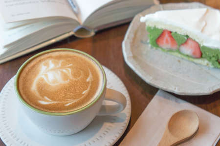Top view of coffee cup and green tea cake , smart phone , book , on table in coffee shop relax timeの写真素材