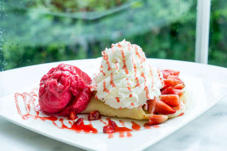 ice cream strawberry crepe dessert on white dish wood table in cafe coffee shop sweet foodの写真素材
