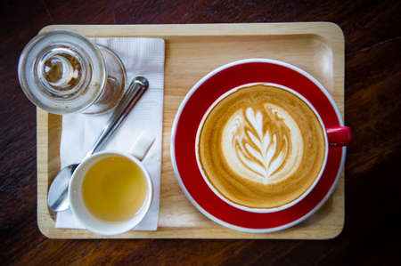 aroma coffee red cup latte art and tasty cake on wood table in coffee shop with vintage dark tone and copy spaceの写真素材