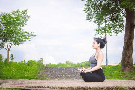 Young woman practicing yoga Everyday Yoga helps in concentration, breath, shape body, strength, help skin brighten. Among the Dharma Air in bright daysの写真素材