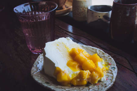 Mango fruit cake on wooden table in restaurant, cafeの写真素材