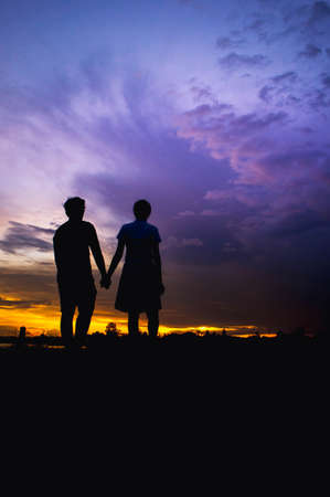 The girl and boy lover is stand and  holding hand silhouette style with cloudy twilight style