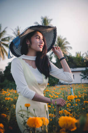 beatiful woman asia style on yellow flower garden and looking smile happy time on the dayの写真素材