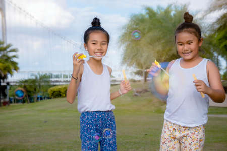 girls happiness funny soap bubble in the park ,Laughing happy with the learning of friendship , lovely sisterの写真素材