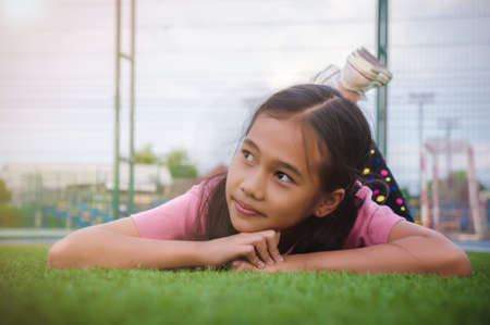 kid asian girl's lie leisurely on the Lawn floorの写真素材