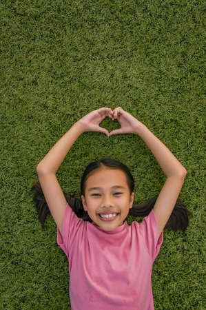 kid asian girl's lie leisurely on the Lawn floor and smile looking at