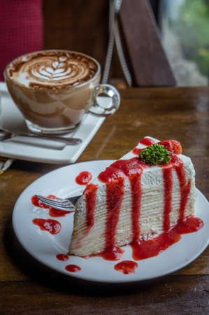 strawberry crape cake on wood table in coffee shop , dessert tasy cake