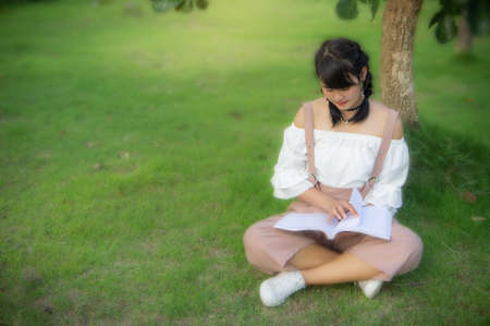 the asian girl's sitting in the park and reading a book on the  dayの写真素材