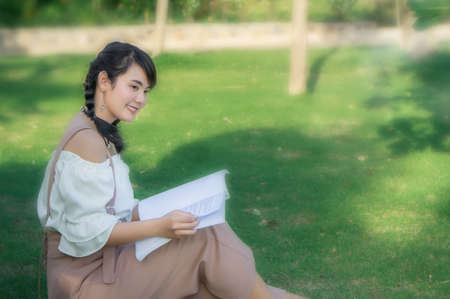 the asian girl's sitting in the park and reading a book on the  day