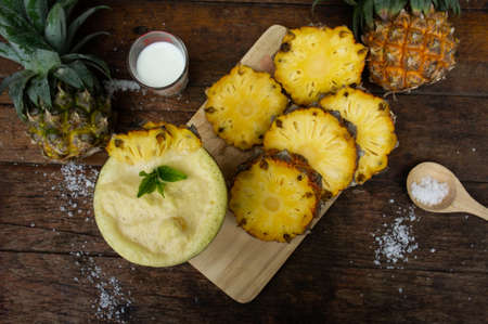 Pineapple juice and pineapple slices cut into pieces on a wooden table. Healthy wood fiber helps to...