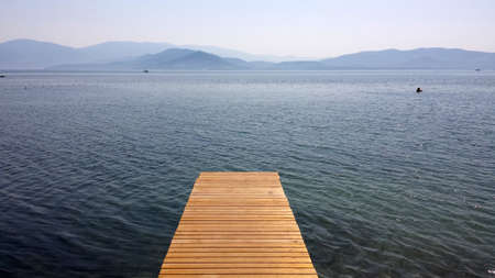 A wooden jetty over the sea and the mountainsの写真素材