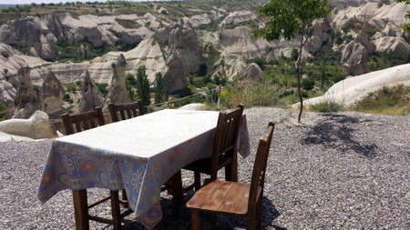 Table and chairs on the stone floor, in the background the beautiful Cappadocia, Turkeyの写真素材