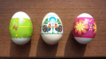 Three colorful Easter eggs on a brown tableの写真素材