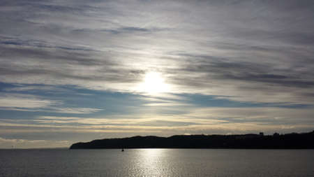 The sun breaks through the calm seaの写真素材