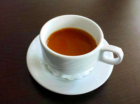 Coffee break. White cup with coffee on a brown table.の写真素材