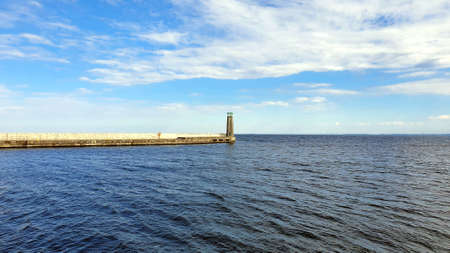 Lighthouse on a calm sea. White clouds in the sky.の写真素材