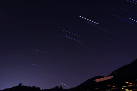 Star trails in the night sky over the village. Long exposure photography.