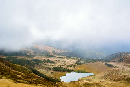 Mountain lake Apshinets or Troyaska before the rain. Gray clouds obscure the view. The fog rises up....