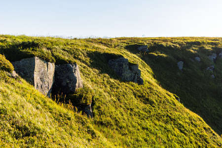 Boulders and rocks in the mountains. Carpathians. Summer, Autumn, Spring. The grass is influenced by the wind. Monument at the top of the mountain. Sunny weatherの写真素材