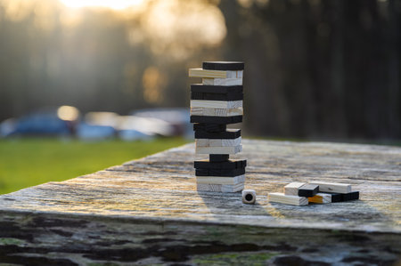 Peaceful rest in nature in sunny weather. The game Jenga, Wooden tower against the background of...