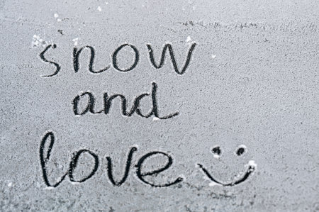 The inscription "snow and love" on the snow with a smiley. Fresh white snow covered the ground. Rest, walk in the fresh air. December, January, February.の写真素材