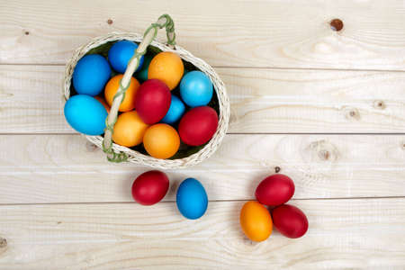Basket full of hand-painted Easter eggs standing on a wooden surface.