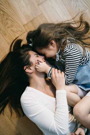 Mom playing with daughter at home laying on the floorの写真素材