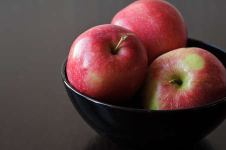 Three red apples on a dark backgroundの写真素材