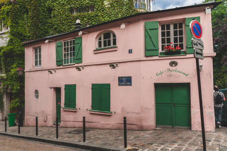 Cafe in old pink house with green doors and window shutters on hill of Montmartre in Parisのeditorial素材