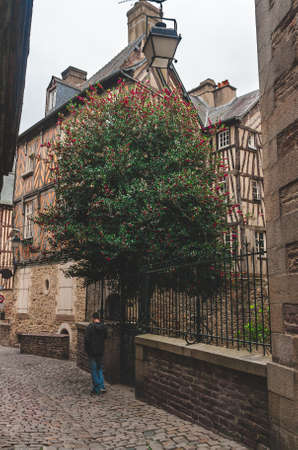 Unidentified person walking along narrow cobblestone alley beside historic half-timbered houses in old town of Rennes, Brittany, Franceのeditorial素材