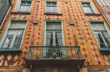 Details of beautiful yellow facade with turquoise balcony and window frames of historic half-timbered house in old town of Rennes (Brittany, France)の写真素材