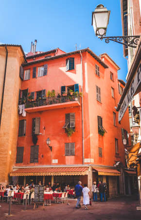 NICE, FRANCE - OCTOBER 13, 2009: People relaxing in cosy open air cafe near colorful traditional house in old town of Niceのeditorial素材