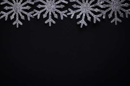Glittery shining snowflakes in line against black background with copy spaceの写真素材