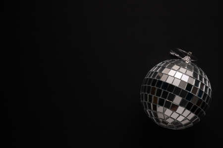 Big bauble made of mirror pieces against black background with copy spaceの写真素材