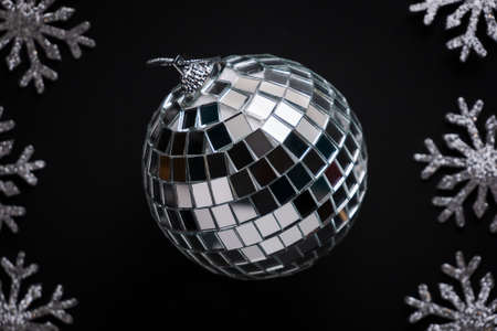 Big shining Christmas bauble made of mirror pieces surrounded by silver glittering snowflakes on...