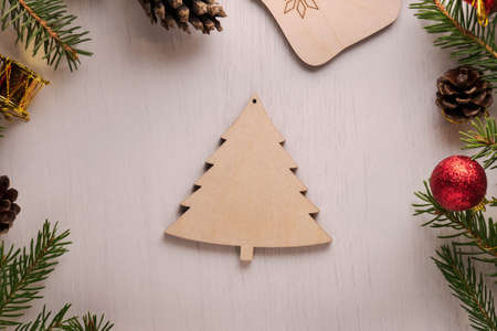 Wooden Christmas tree decoration surrounded by spruce twigs, pine cones and red and golden...