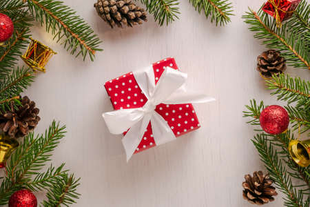 Christmas square present wrapped in red paper with white polka dots and big white bow, surrounded by...