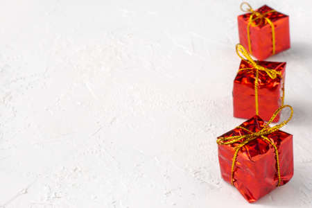 Red gift boxes in line on white textured background with copy space