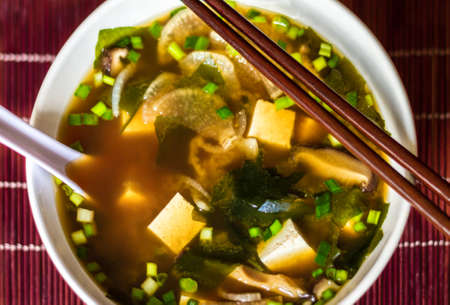 Japanese traditional miso soup with tofu, spring onions, wakame seaweed, served in white bowl with...