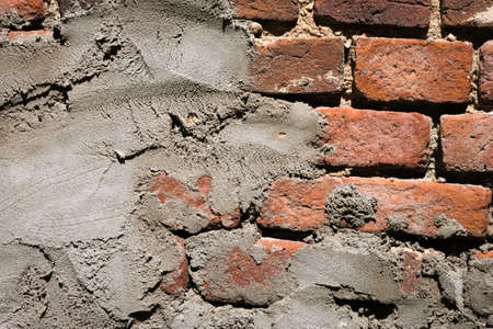Close up of old worn grunge red brick wall covered with layer of plaster. Rough surface. Abstract...