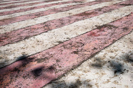 Weathered, worn out red and white stripes, diagonal signal lines. Striped pedestrian crosswalkの写真素材