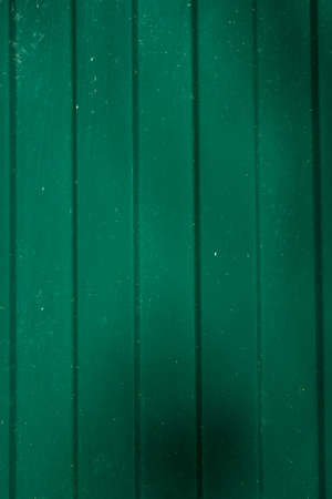 Corrugated metal wall background of green fence with shadows. Vertical shot. Copy spaceの写真素材