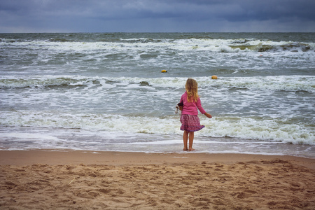 Pretty blond girl on the bank of the rough seasの写真素材