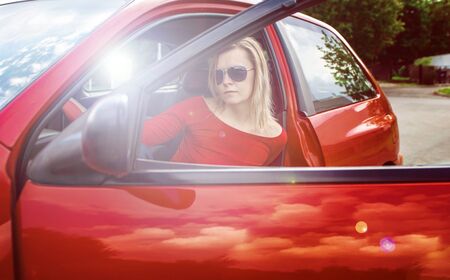 Girl in a red shirt and driving a red car.の写真素材
