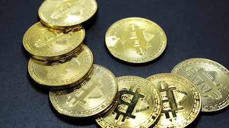 Several coins of gold bitcoins on a dark background.の写真素材