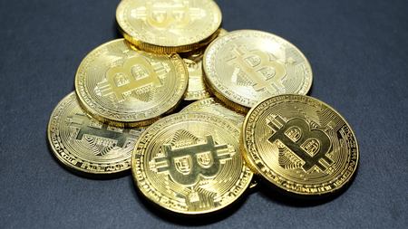 Several coins of gold bitcoins on a dark background.の写真素材