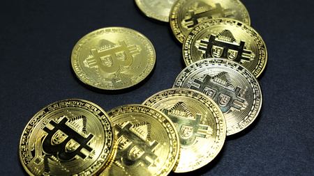 Several coins of gold bitcoins on a dark background.の写真素材
