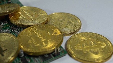 Several coins of bitcoins and a strip of electronic memory on a light background.の写真素材