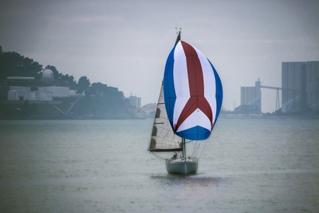 A beautiful yacht under a bright sail in the sea in cloudy weather.の写真素材